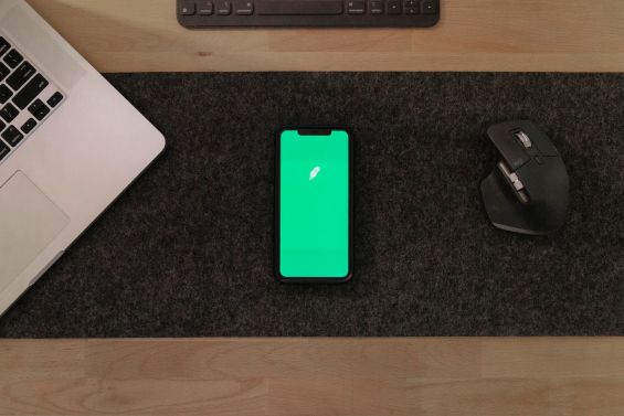 phone with green screen on black desk with laptop and mouse