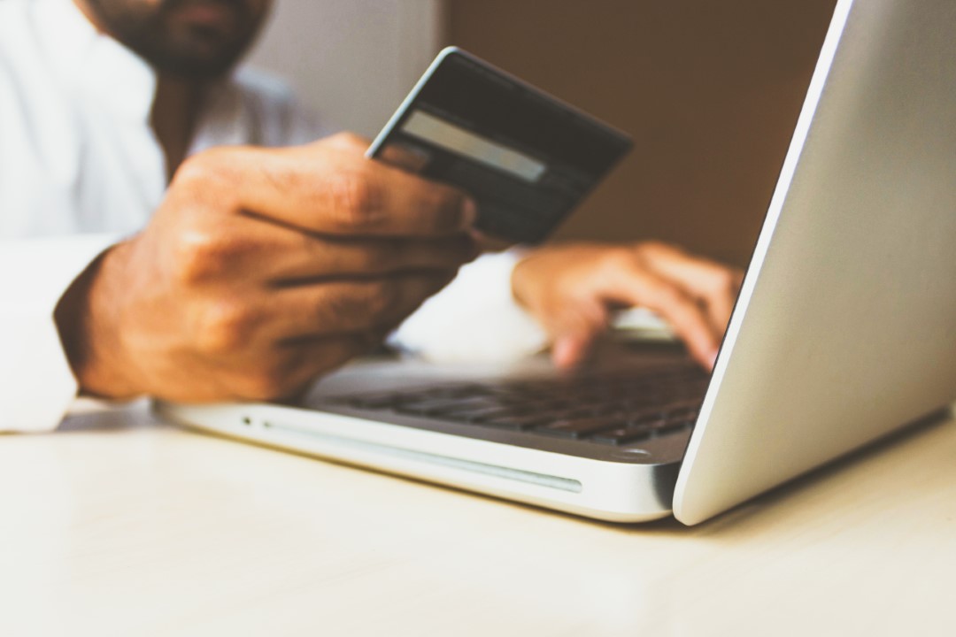 person holding a credit card shopping online on the computer